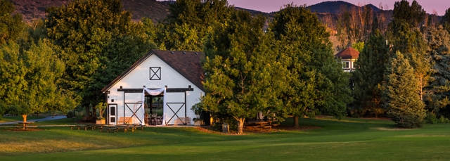 A white building with open barn doors at dusk with mountains behind the building