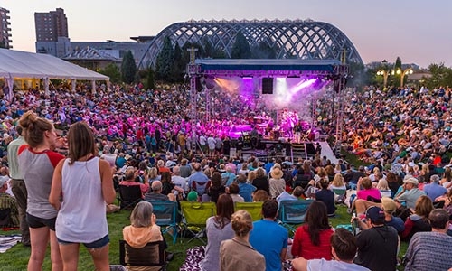 a crowd watches performers on stage at the Summer Concert Series at the Gardens