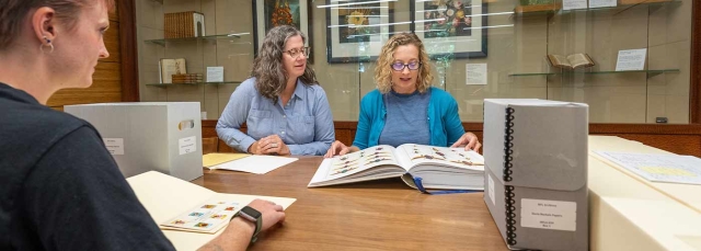 Three people doing research in the Edward P. Connors Rare Book Reading Room.