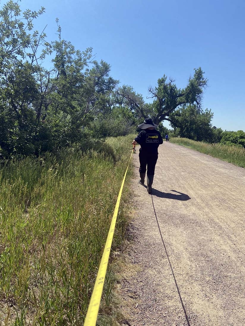 Person walking with measuring tape stretched behind them along a path