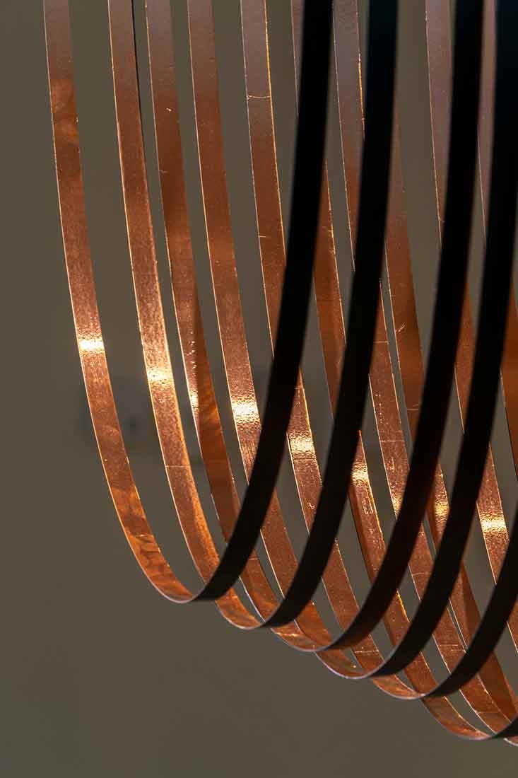 Steel bands and copper foil casting a shadow on the ground. 