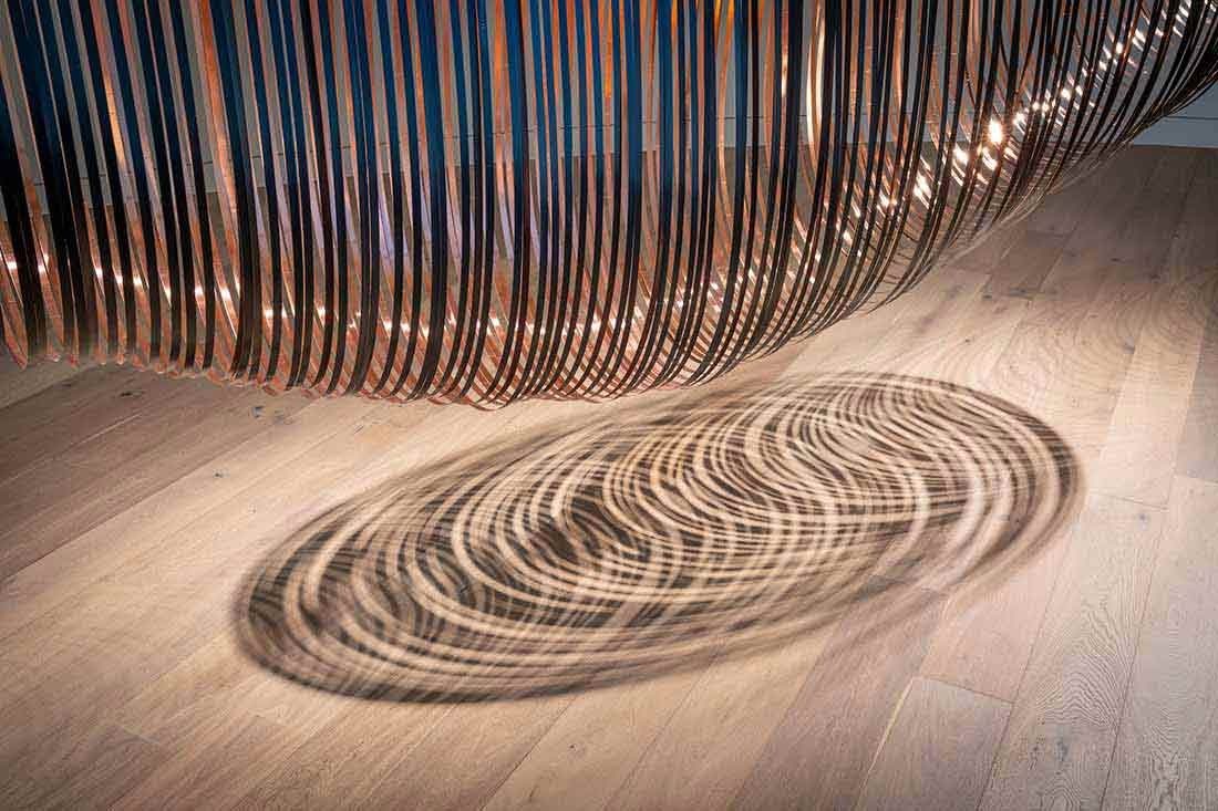 Steel bands and copper foil casting a shadow on the ground. 