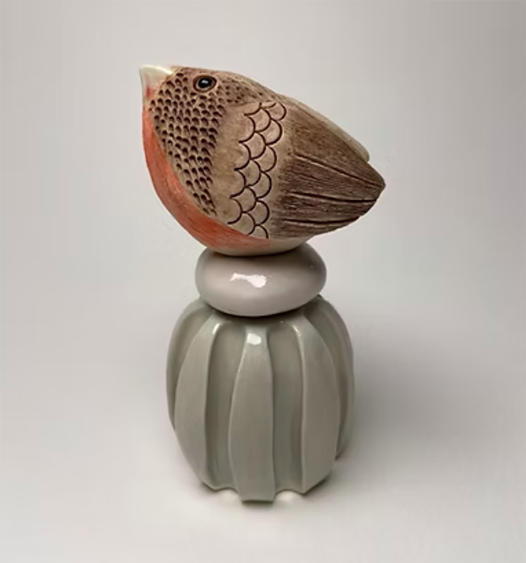 Porcelain bird with red chest, brown feathers, sitting on a post