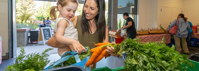 Woman and child choosing a bunch of carrots at the CSA pickup