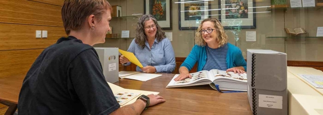 Three adults in the Edward P. Connors Rare Books Reading Room