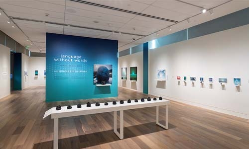 Gallery showing a blue wall with white display case in foreground