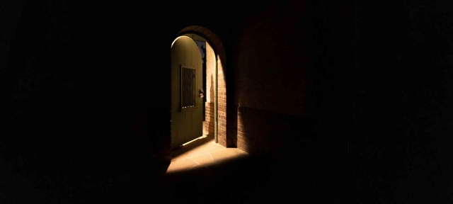 Dark shadowy doorway lit from behind. Door is partially open.